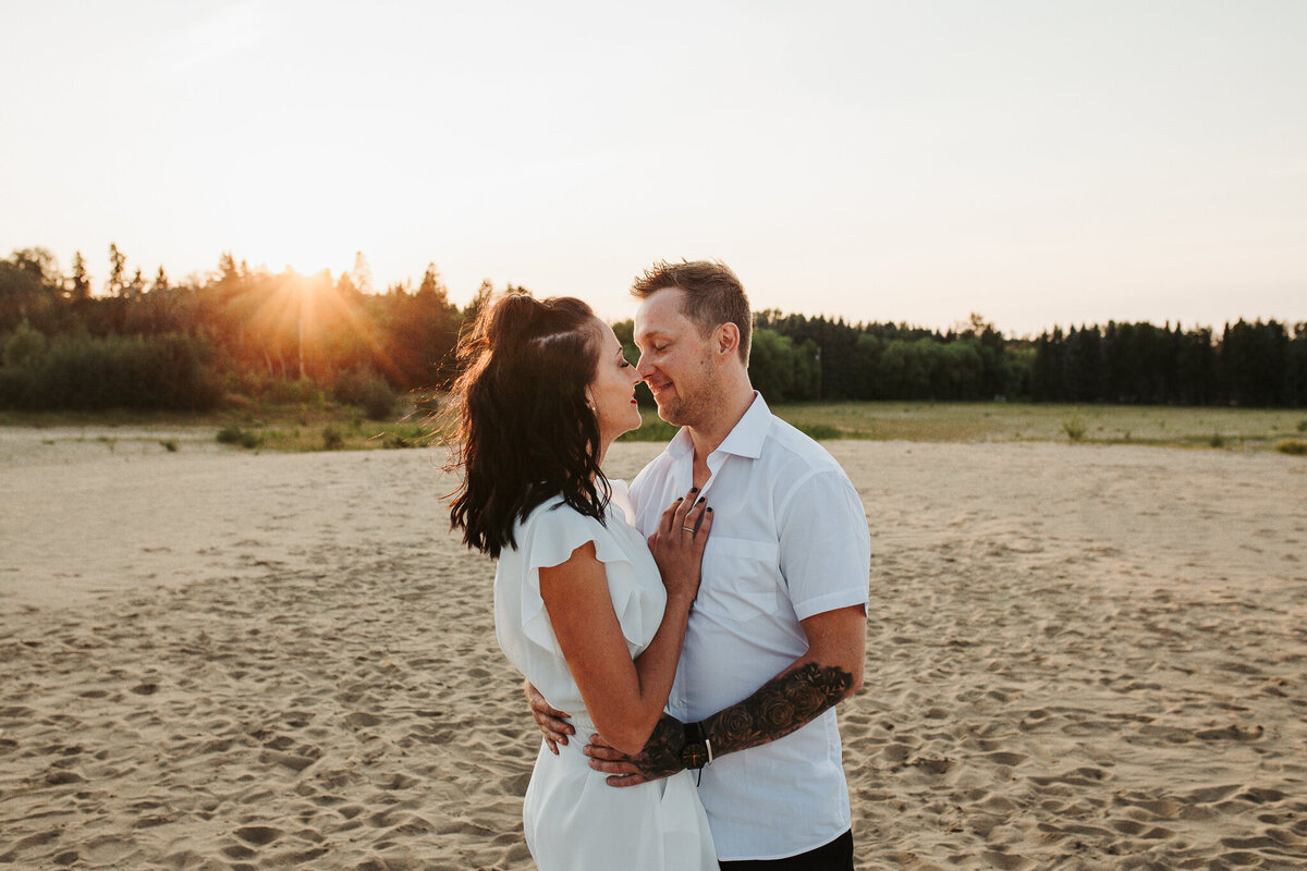 a couple wearing all white looking at each other during sunset