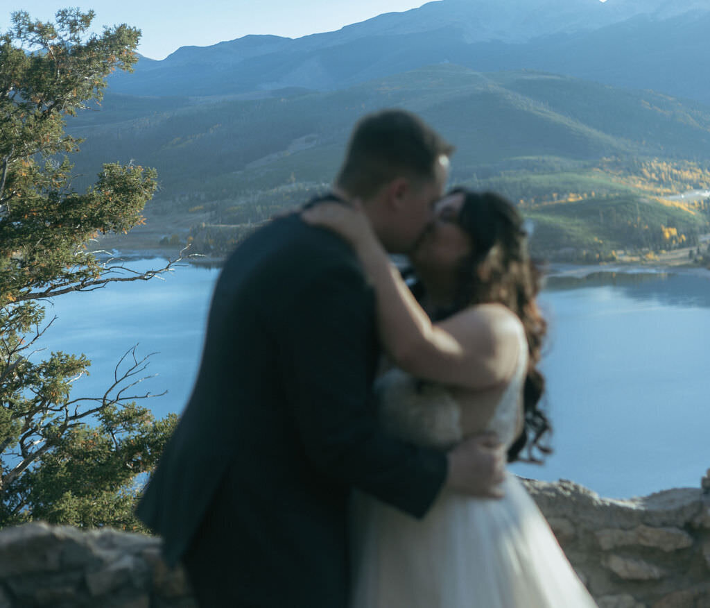 A newlywed couple kissing in the mountains.