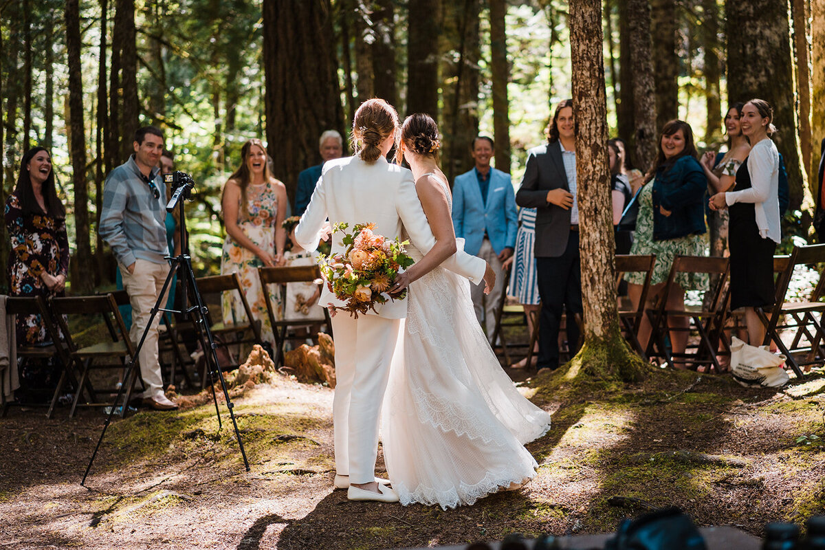 Two brides looking back at their guests after recessing out of their intimate wedding ceremony in Olympic National Park!