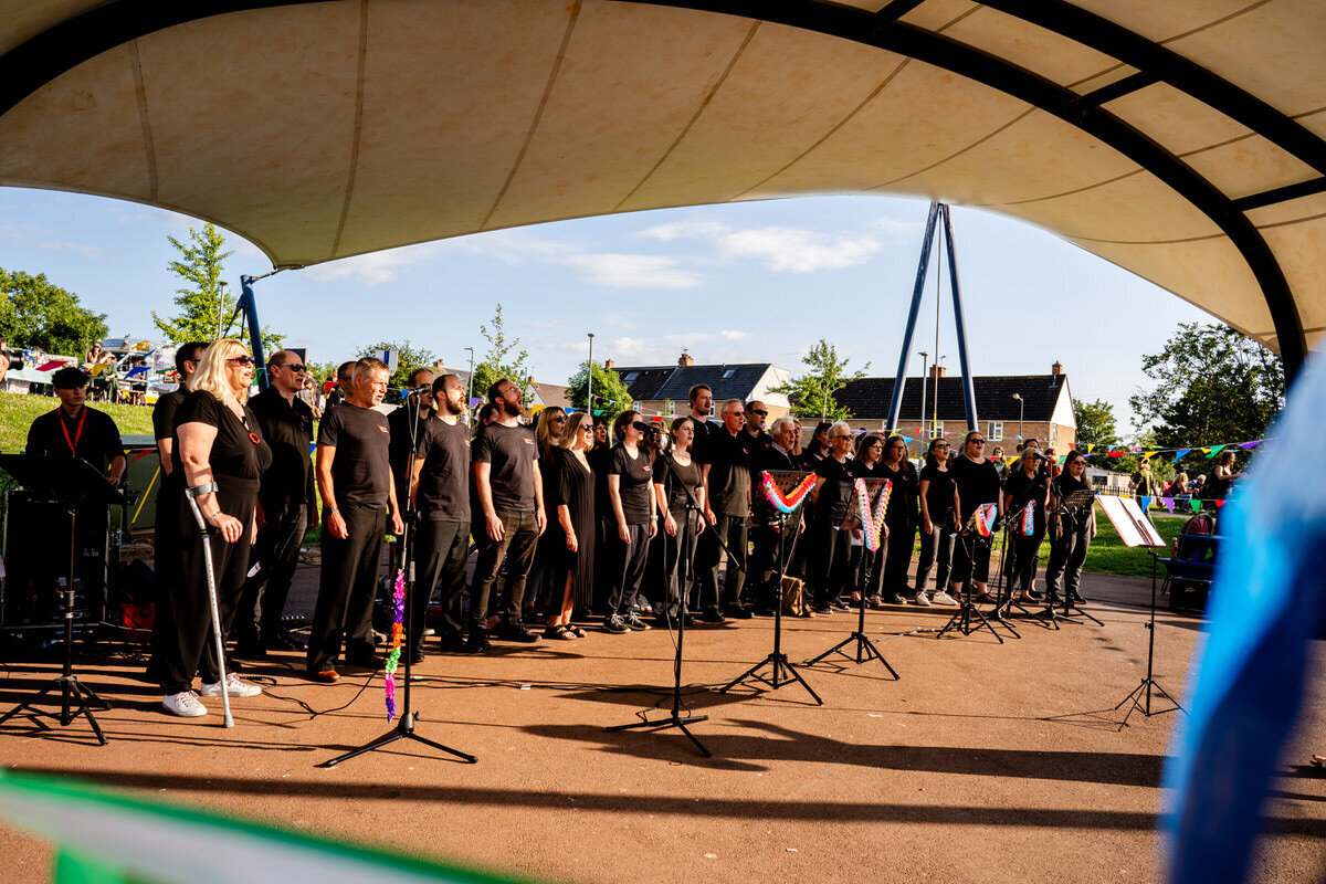 press release photograph of two women by a vegetable patch holding pitch fork and spade.