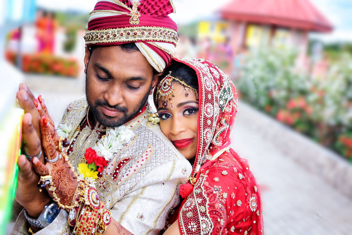 Hindu bride and groom embrace wearing traditional wedding clothes. Photo by Ross Photography, Trinidad, W.I..