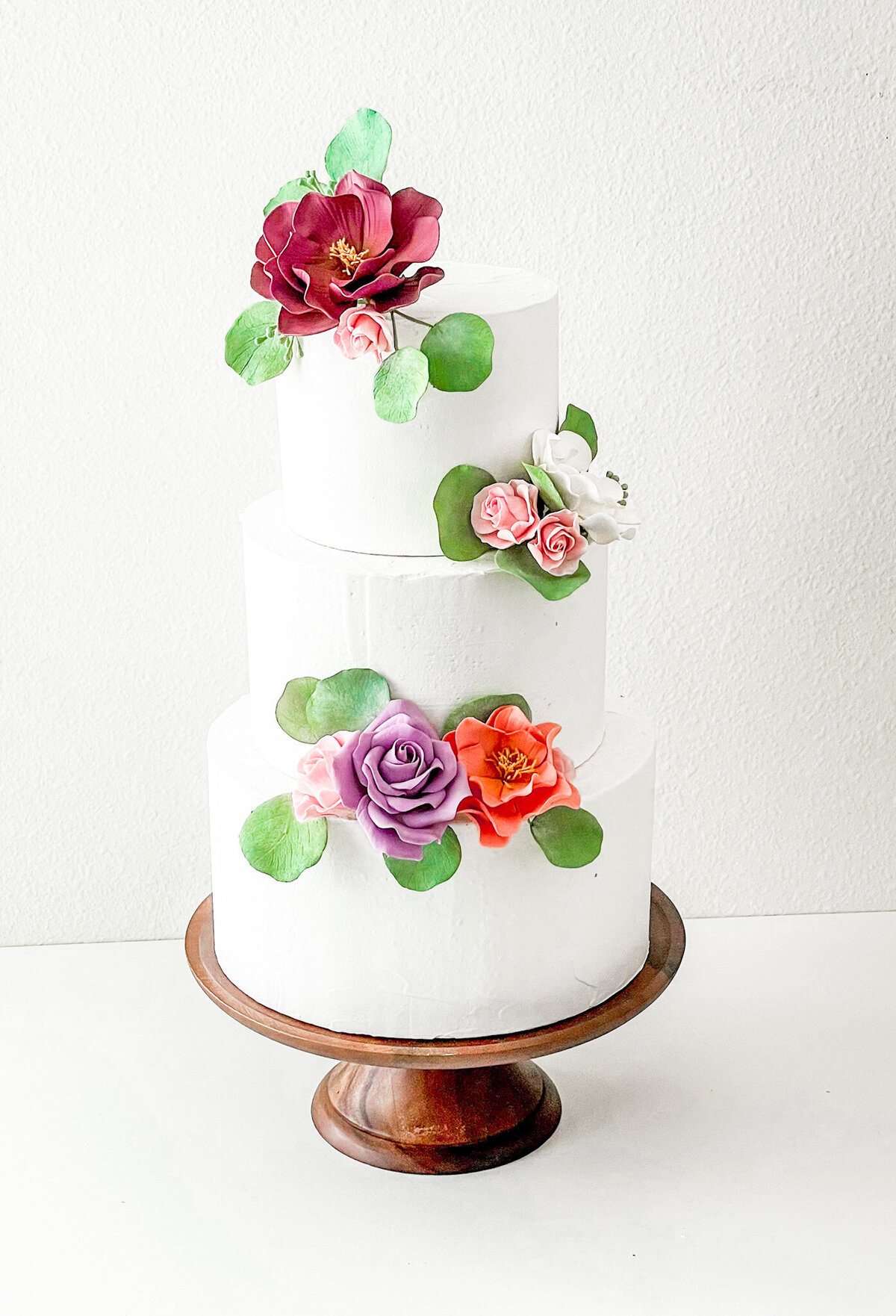 three tier buttercream cake with sugar flower roses and eucalyptus