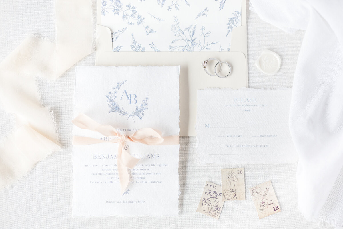 Light and bright invitation suite flat lay with deckled edge paper.
