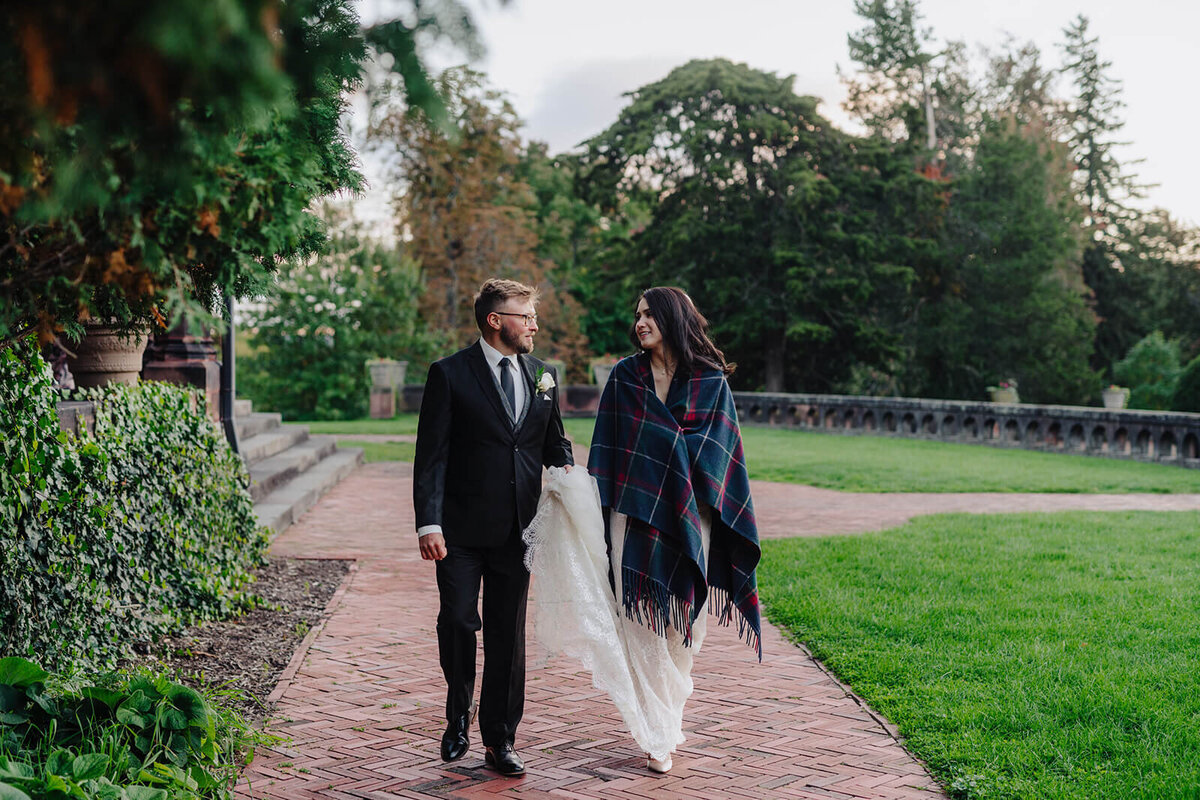 Bride and groom walking along with bride wrapped in a shawl