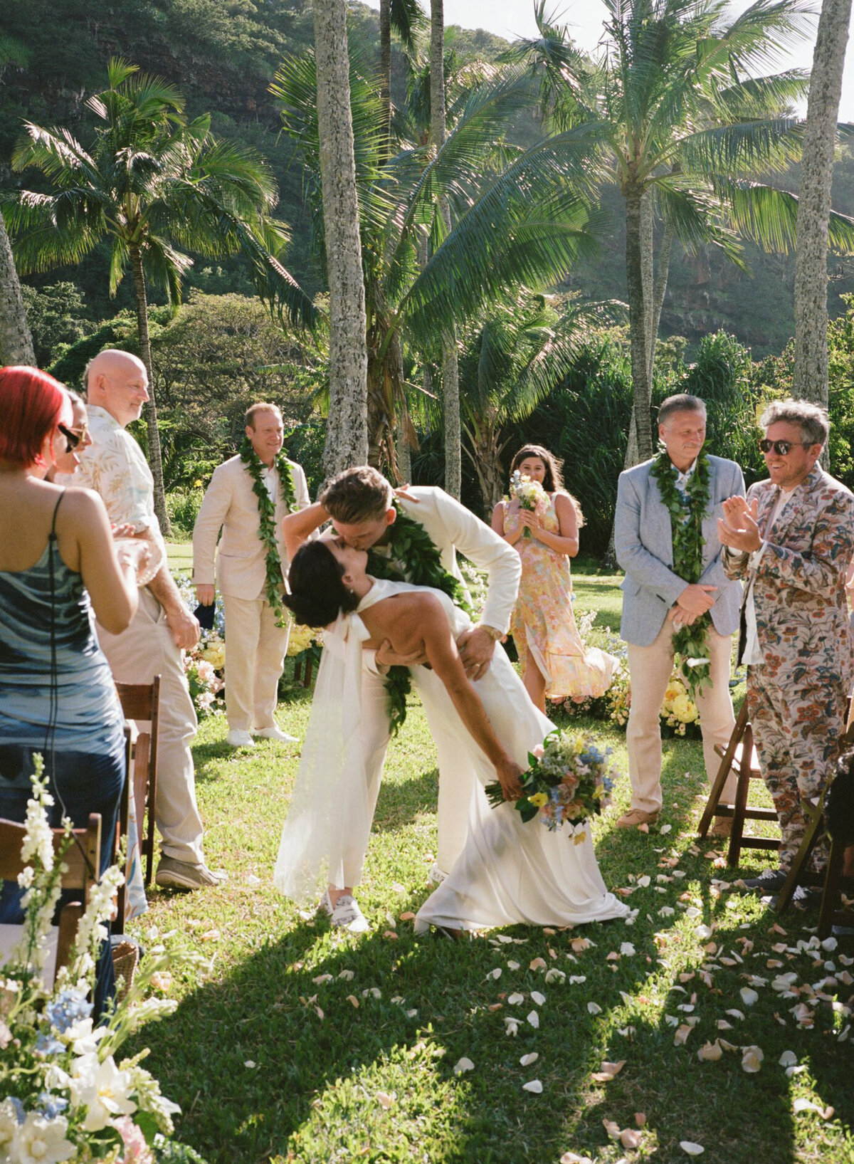 Chic, candid moment of a couple sharing their first kiss down the aisle at a tropical wedding, captured on film in a documentary style — by Kate Winters Photography.