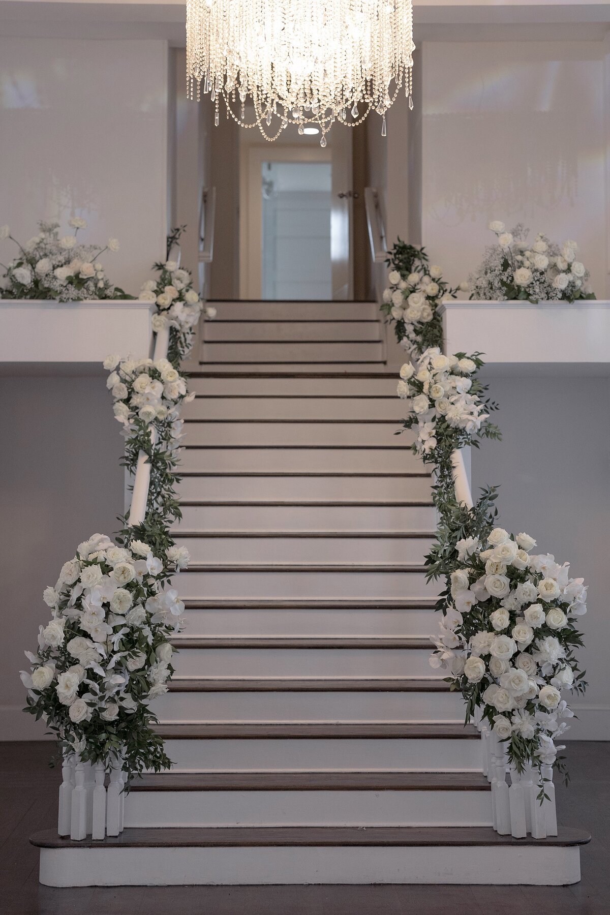 Cream floral decor lines the staircase in the ballroom at Belle Mer Newport.