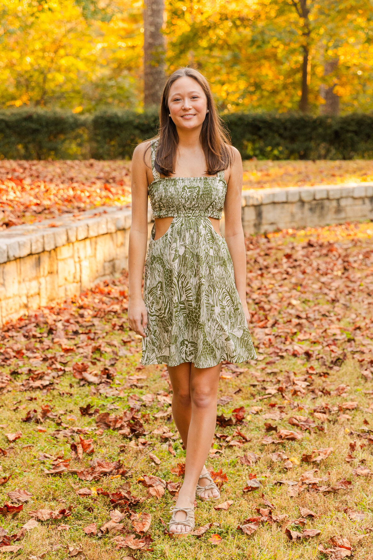 gilr walking toward the  camera during photo session in the middle of dead leaves