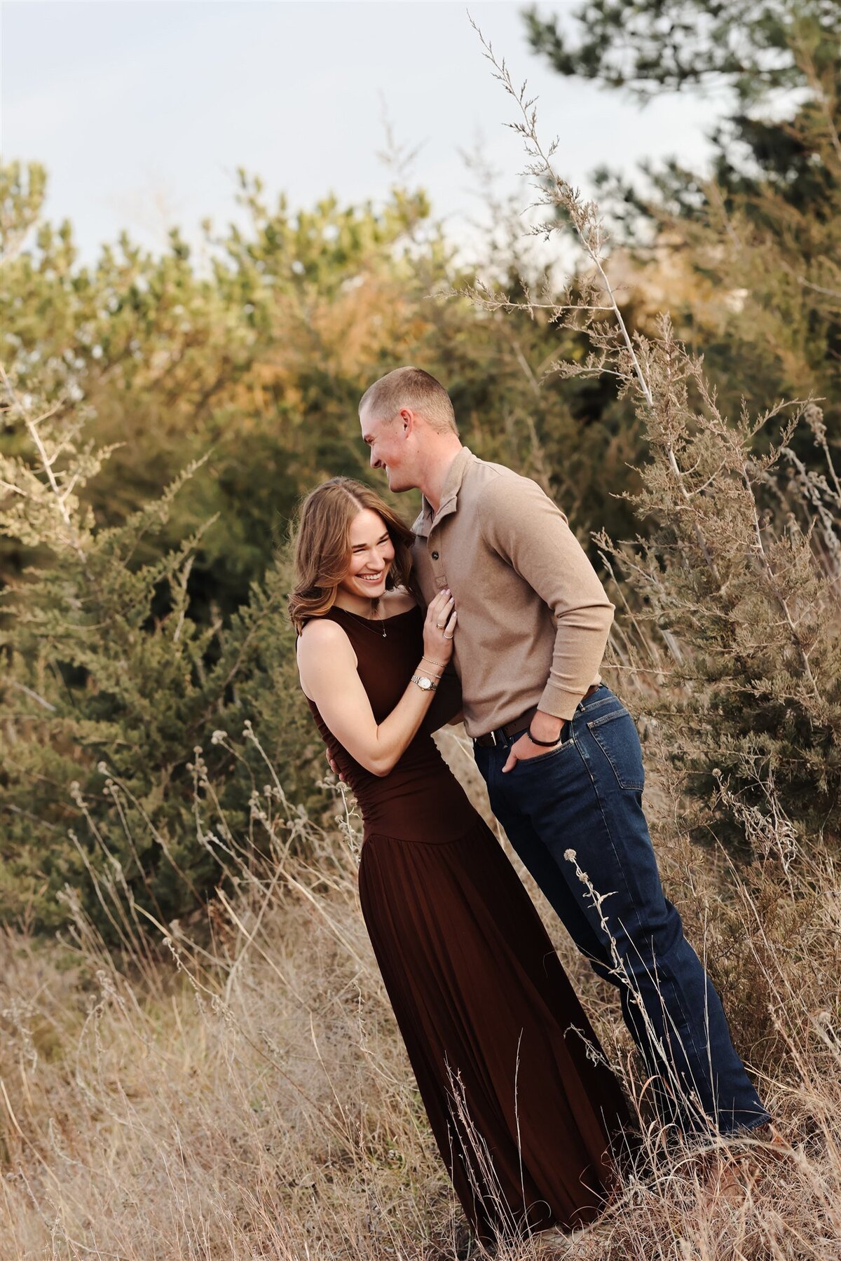 Couple laughing in tall grass wearing brown and tan