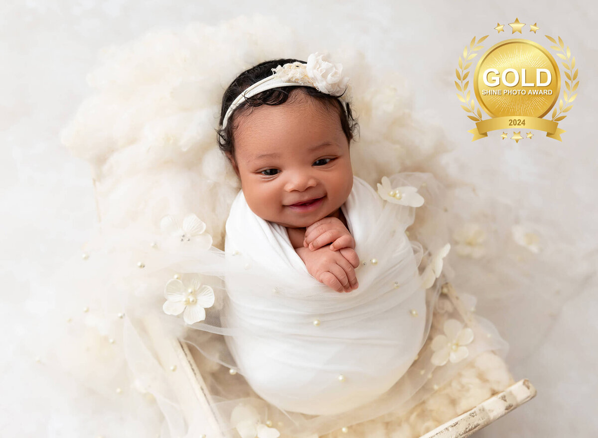 newborn baby girl wrapped in white smiling  at her first photo session in Brooklyn NYC