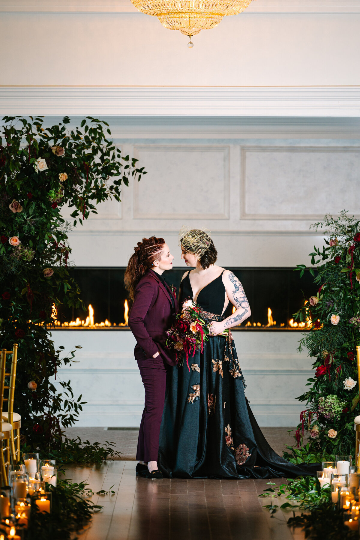 Brides at wedding alter surrounded by greenery