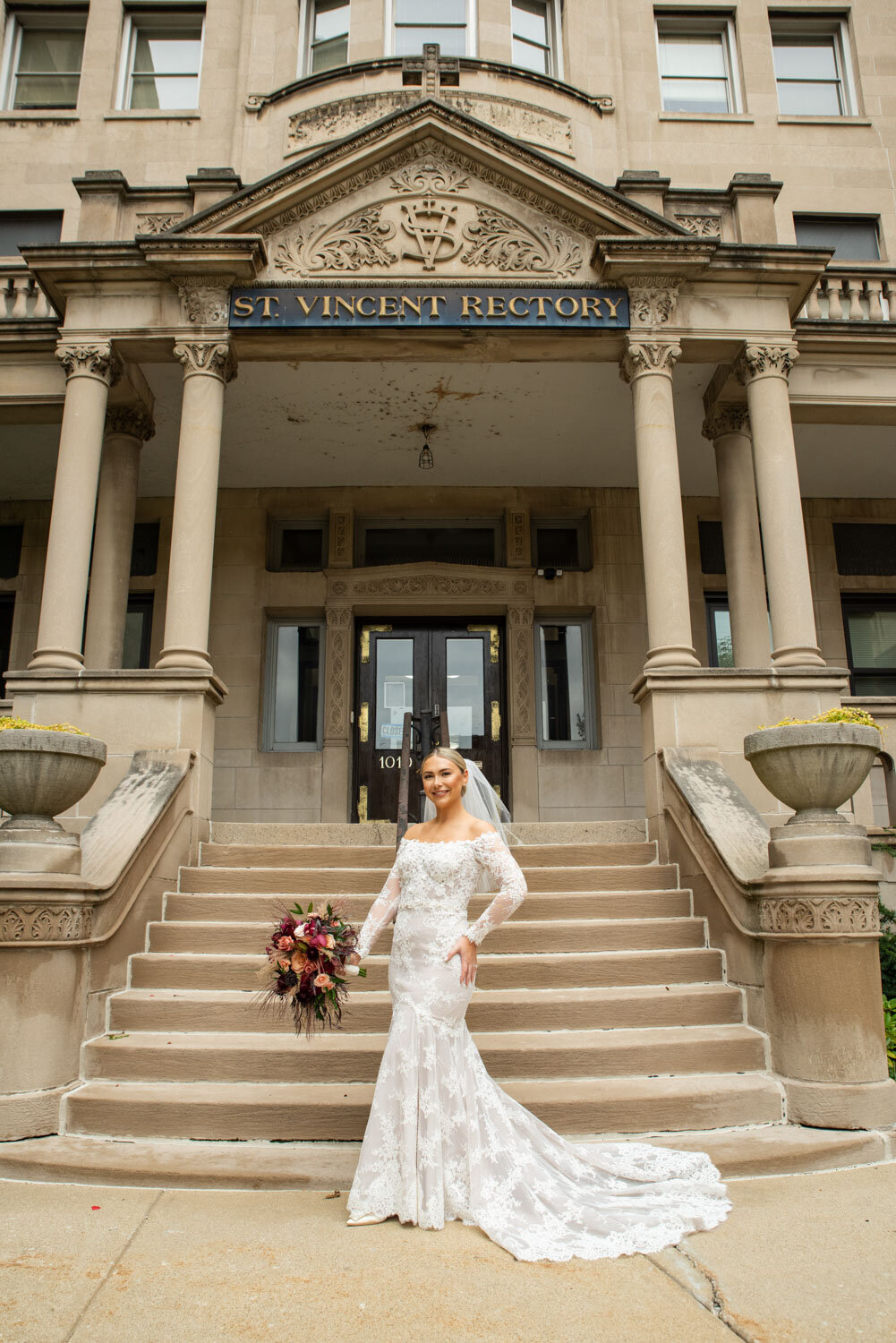 A woman in a wedding dress stands in front of the st. vincent rectory