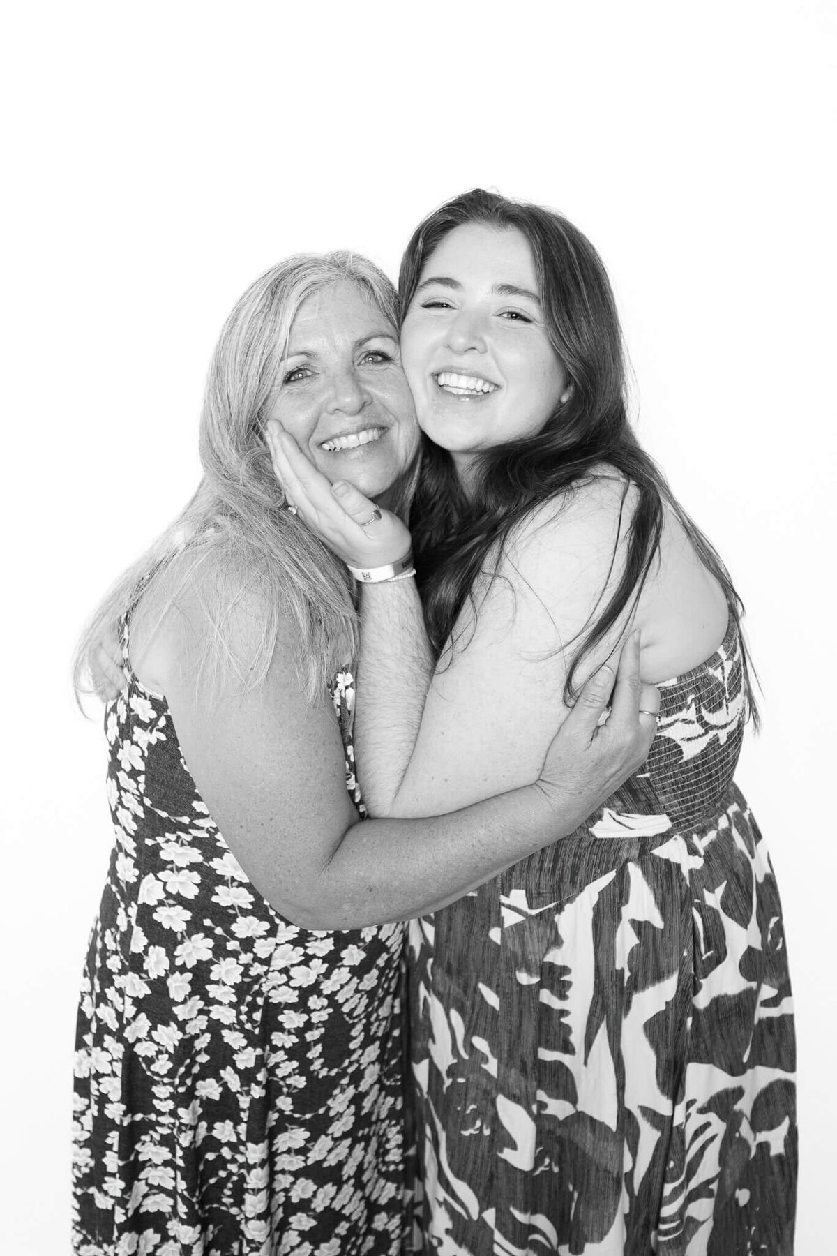 A joyful black and white portrait of two women embracing and smiling, captured by Monochrome Portraits, a Phoenix photo booth experience.