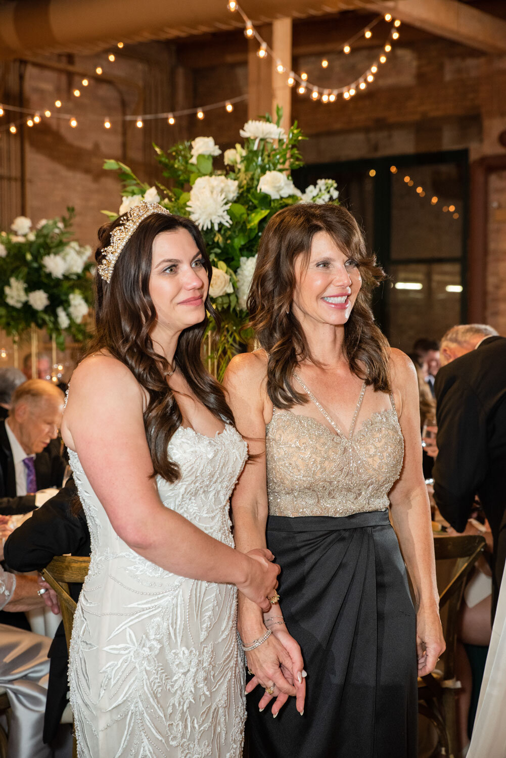 Two women standing next to each other with flowers in the background