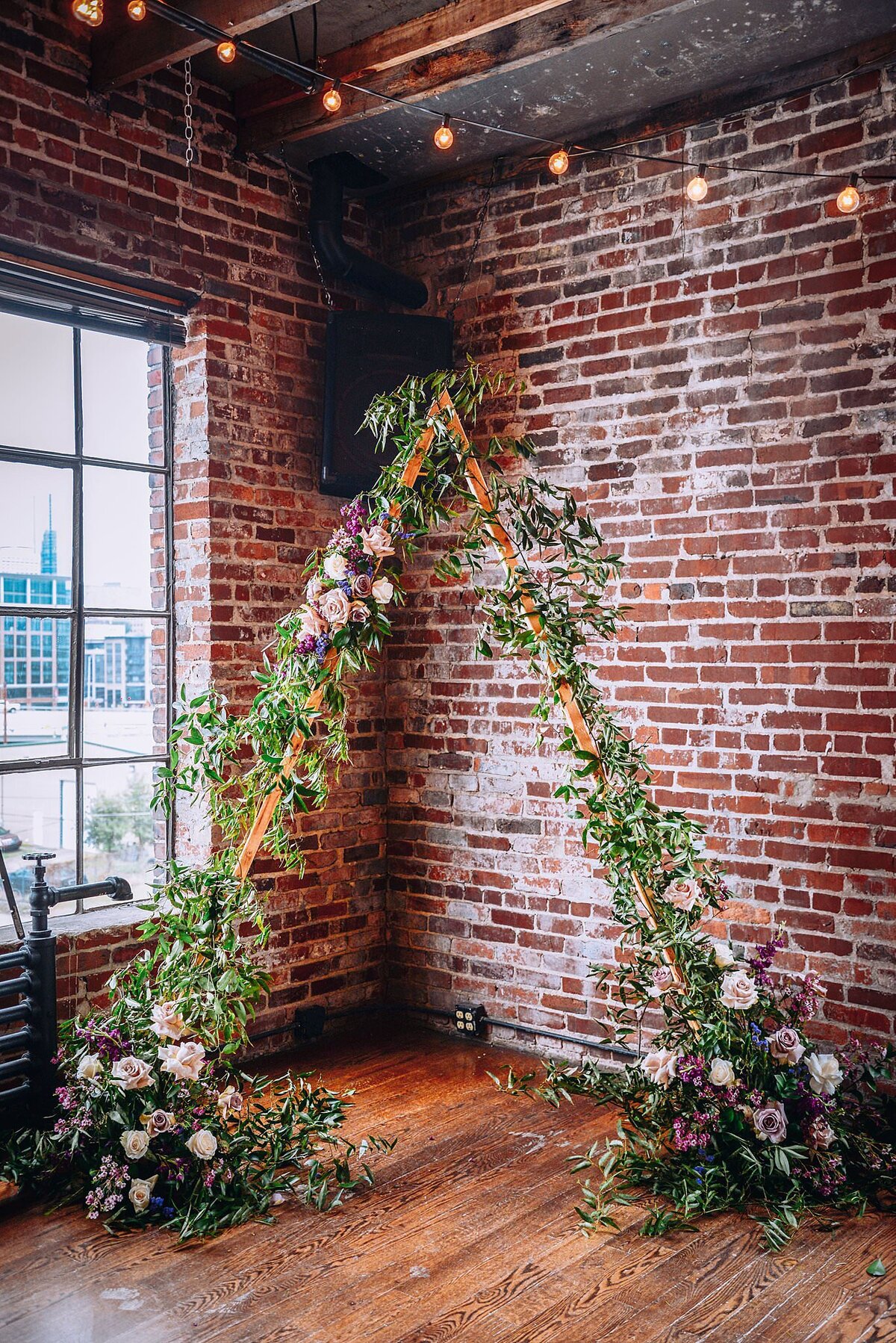 Wooden triangle covered with greenery, and flowers at the two bases in white and lavender