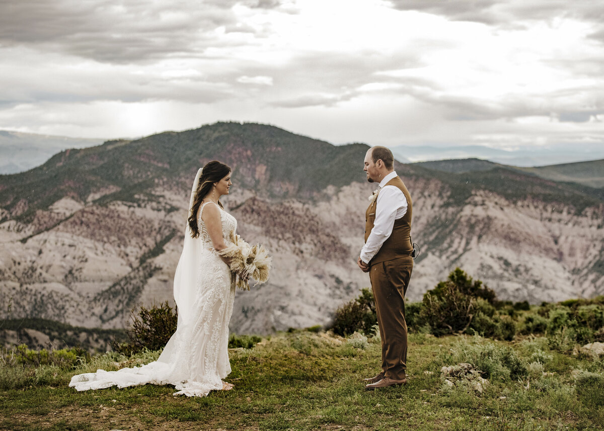 A bride and groom exchange a meaningful gaze amidst a picturesque Colorado mountainous landscape, encapsulating a moment of love and commitment in the tranquility of nature taken by jen Jarmuzek photography a Minneapolis wedding photographer