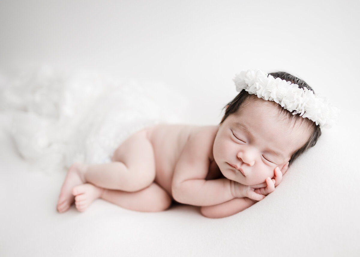 side laying newborn with white floral crown, photographed in Los Angeles, CA