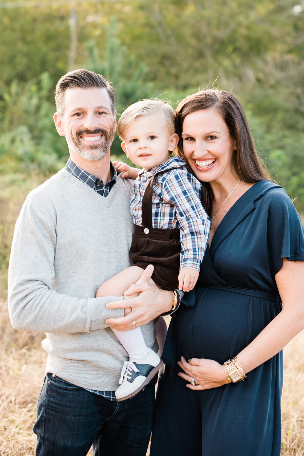 Family smiles for a portrait with their toddler at a Raleigh family photo session. Photographed by Raleigh NC Family Photographer A.J. Dunlap Photography.