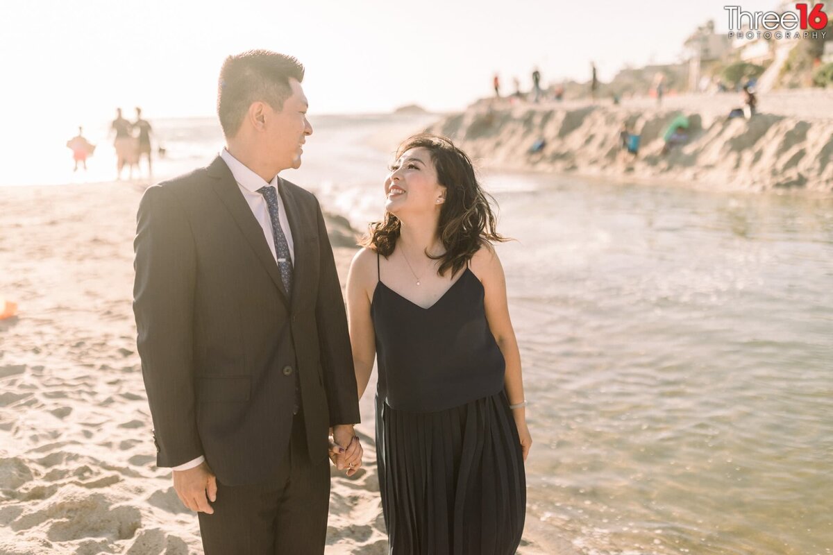 Engaged couple share smiles as they walk along Aliso Beach