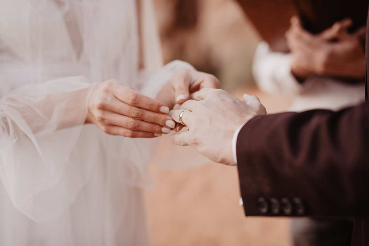 Utah elopement photographer captures bride putting ring on Groom's finger in Arches National Park