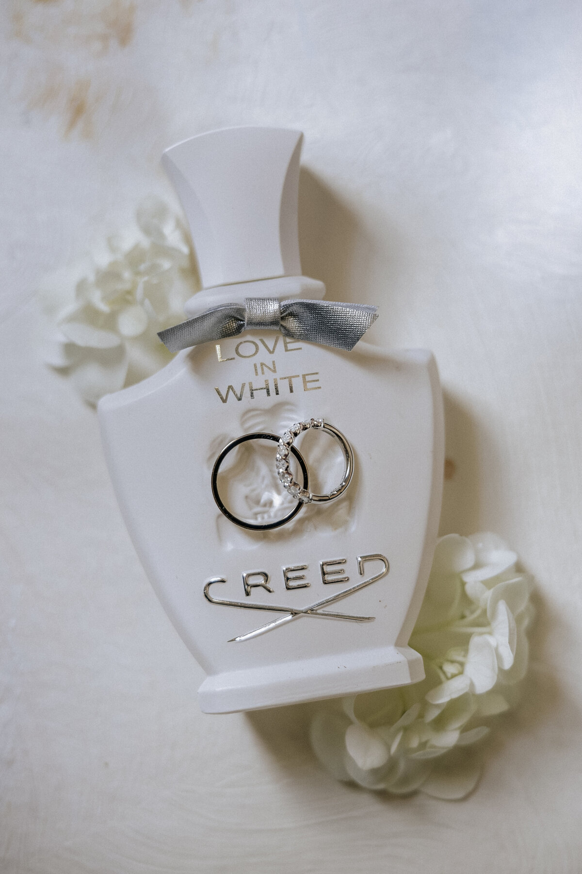interlocking-wedding-rings-resting-on-love-in-white-creed-perfume