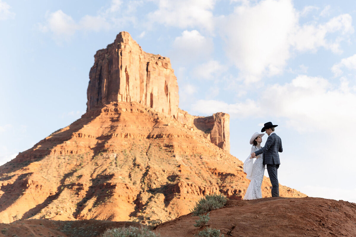 Moab wedding photographer work with bride and groom holding hands in a Utah national park.