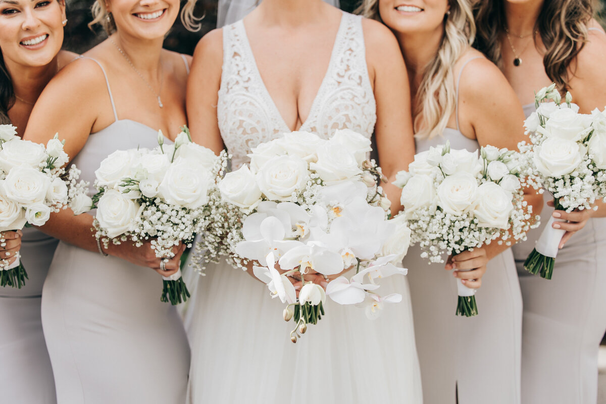 Close up photo of bridesmaids holding white wedding bouquets