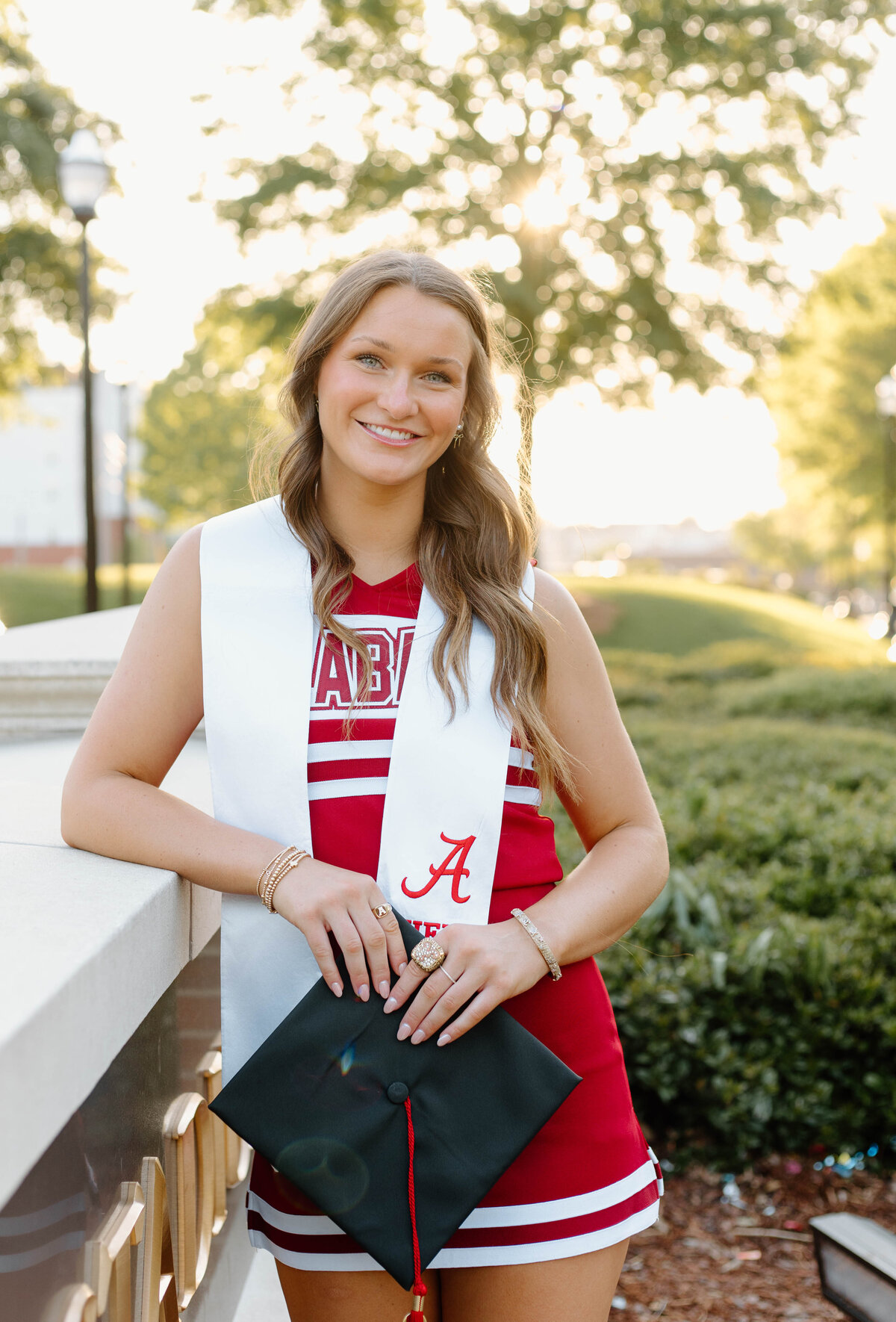 UA cheerleader taking graduation pictures infront of the Bryant Denny Stadium
