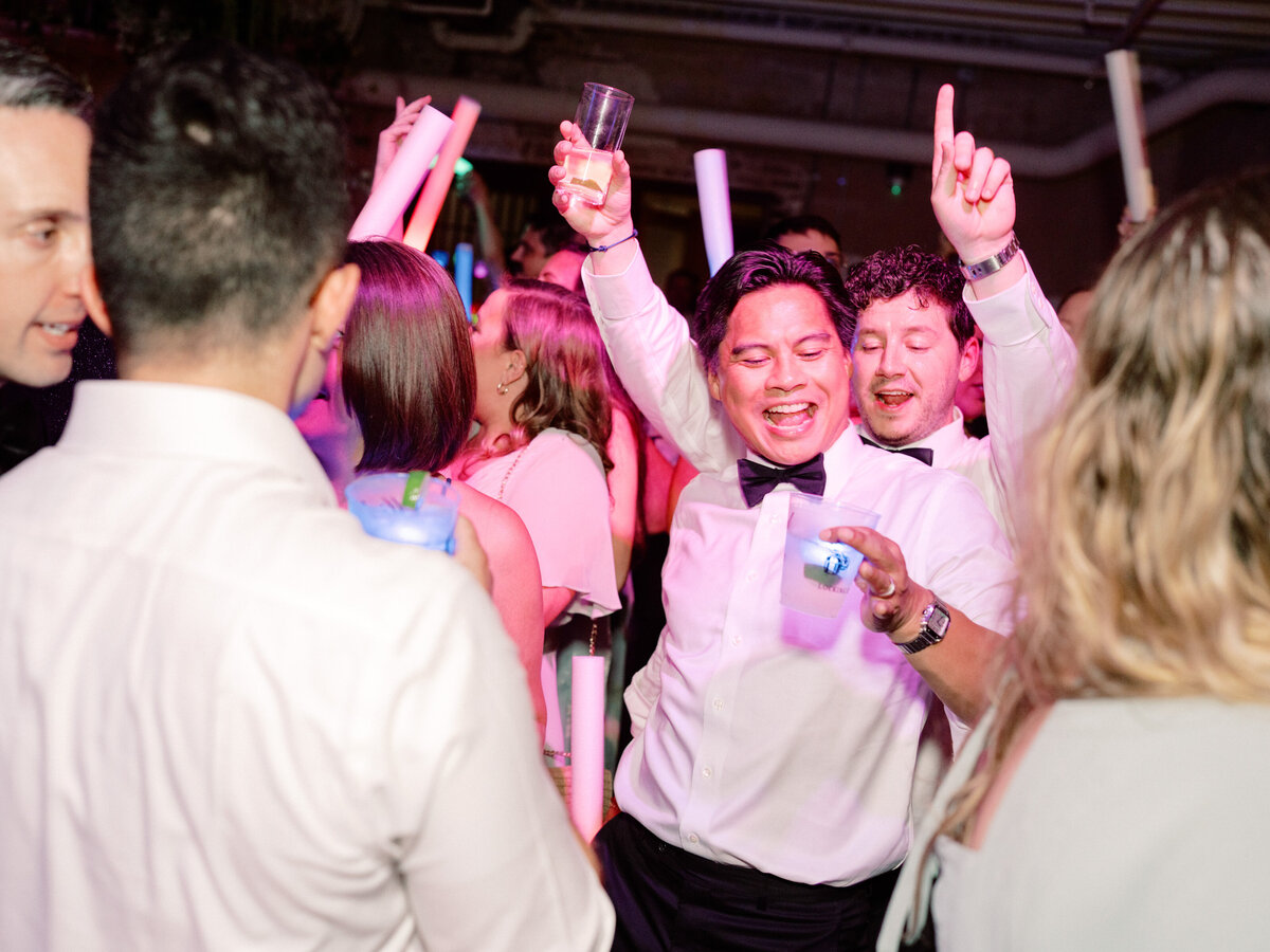 A vibrant scene captures the essence of celebration with joyful individuals dancing and raising drinks during a lively event full of energy and excitement.