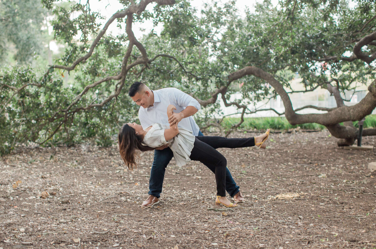 A betrothed man dips his fiancee during their engagement session at Hermann Park in Houston, Tx.