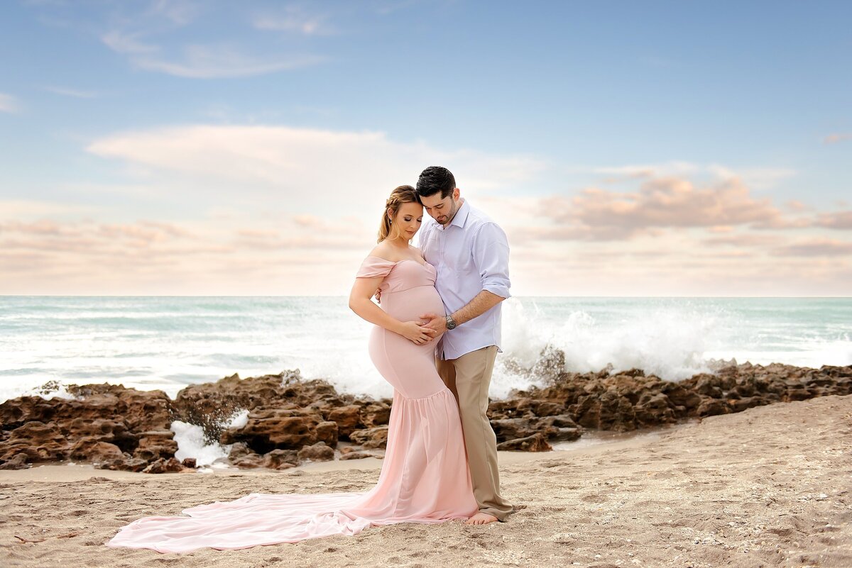 Beach maternity pictures in South Florida featuring a flowing gown and ocean backdrop.