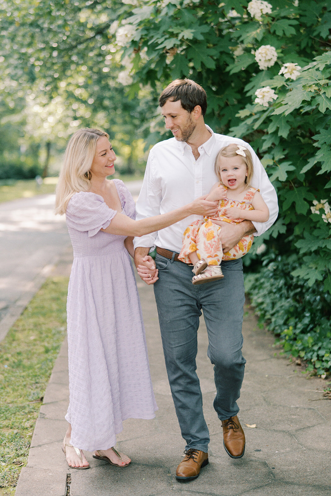 mom tickling baby girl as they walk as a family