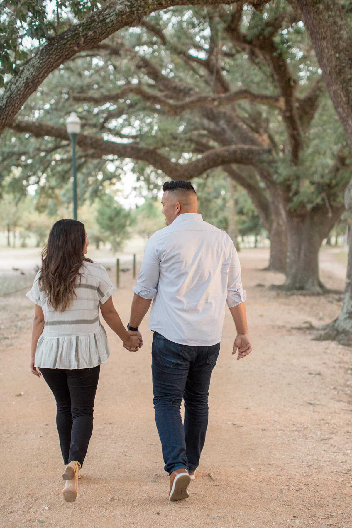A hispanic couple walk, hand in hand, away from the camera