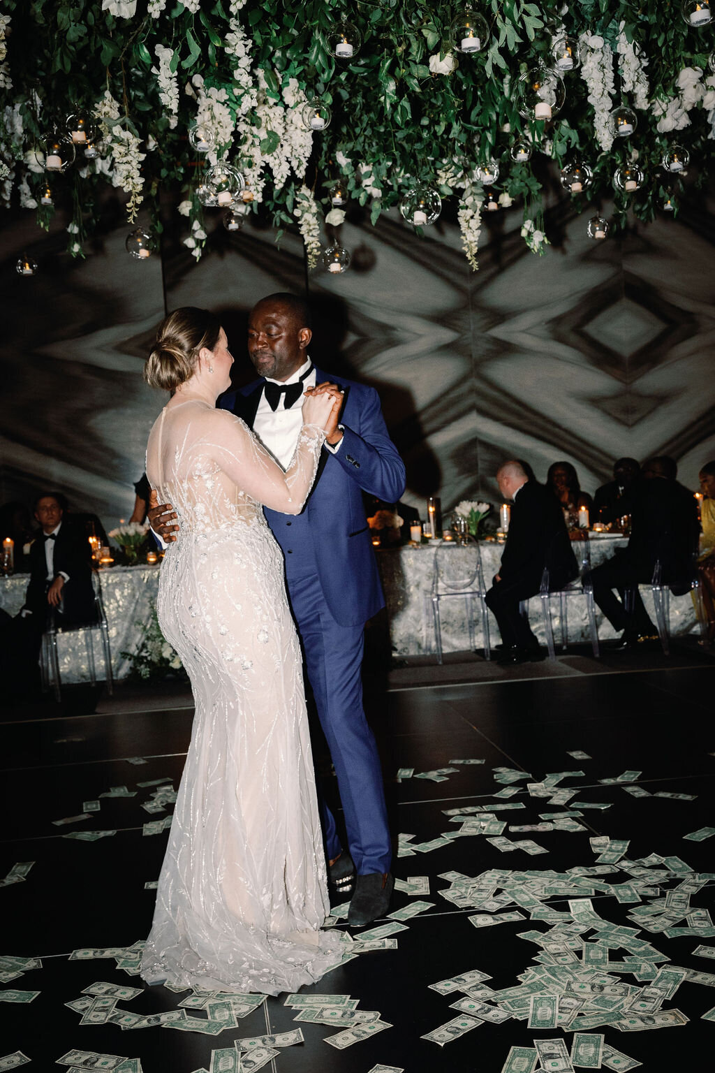 Bride and groom dancing at wedding reception with money thrown on the dance floor.