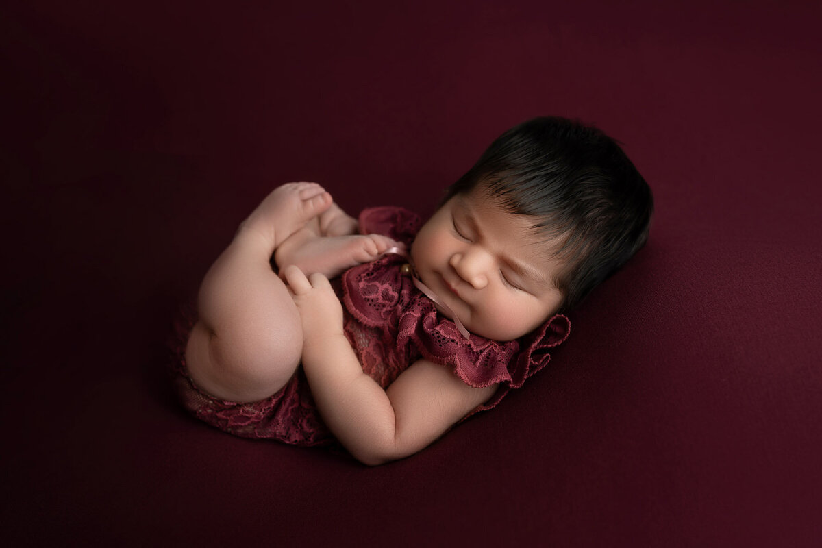 Newborn baby burgundy wrap sleeping pose Cedar Park professional photographer
