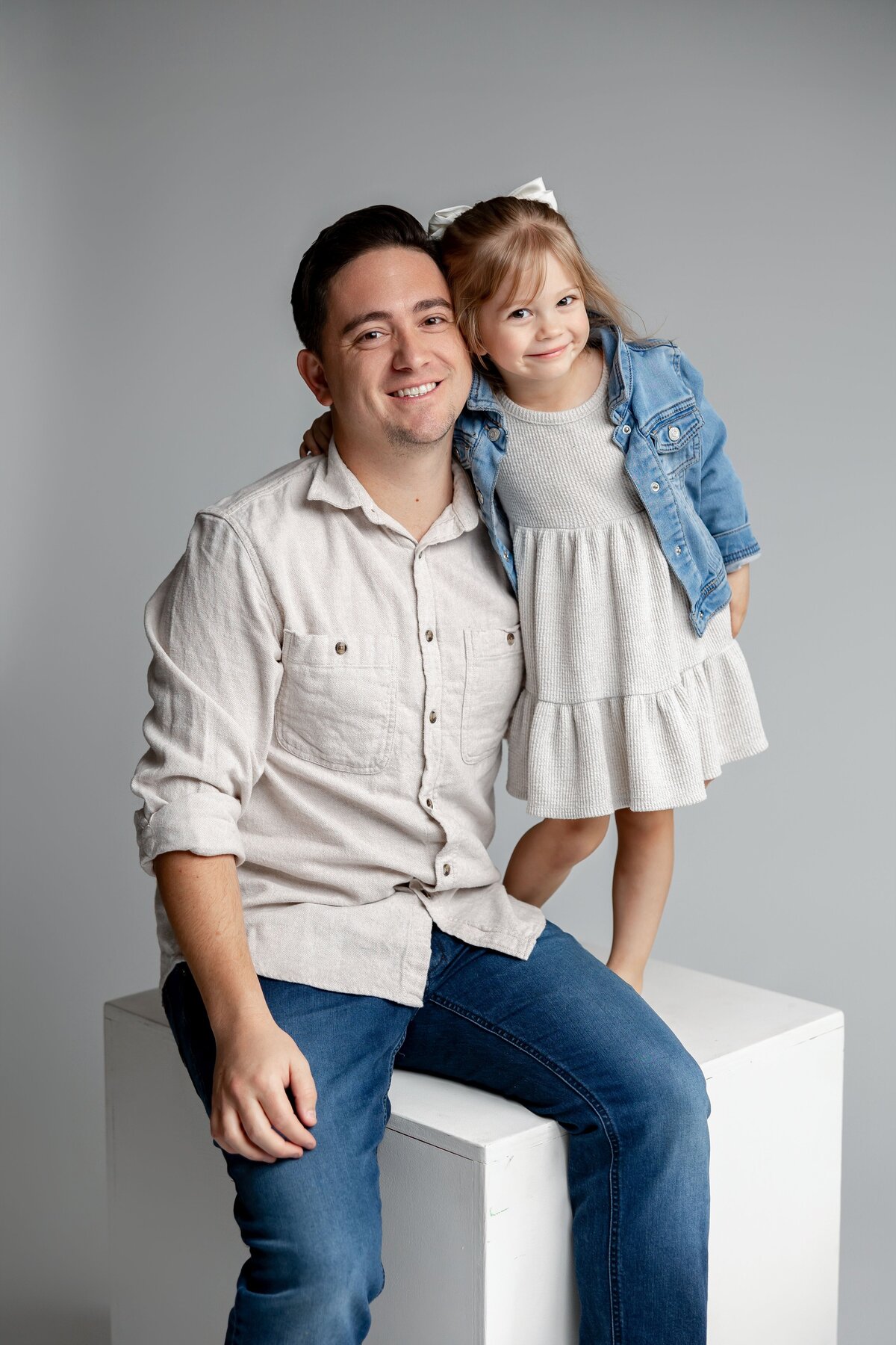 Father with young daughter on his lap, both dressed in soft neutrals and denim. Photographed by Yucaipa family photographer Kaitlyn Dawn Photography.