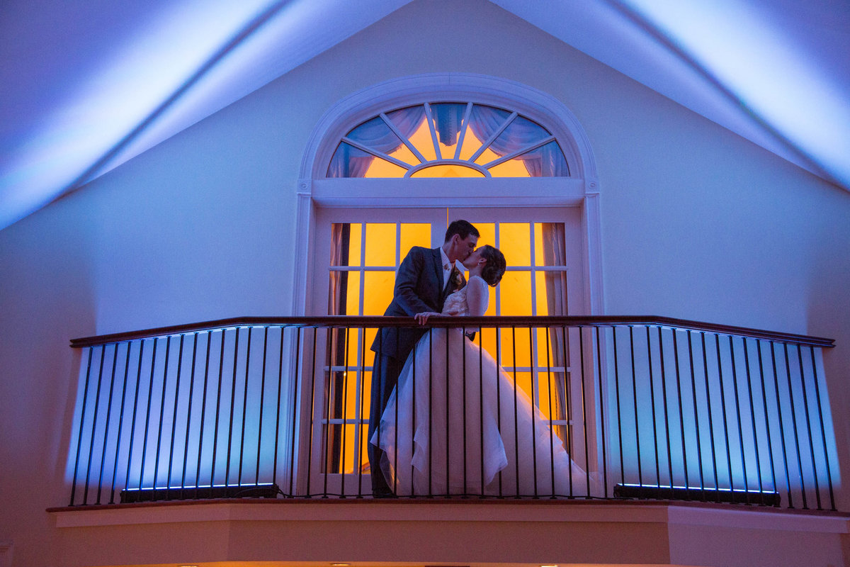 bride and groom kissing on balcony at The Riverhouse