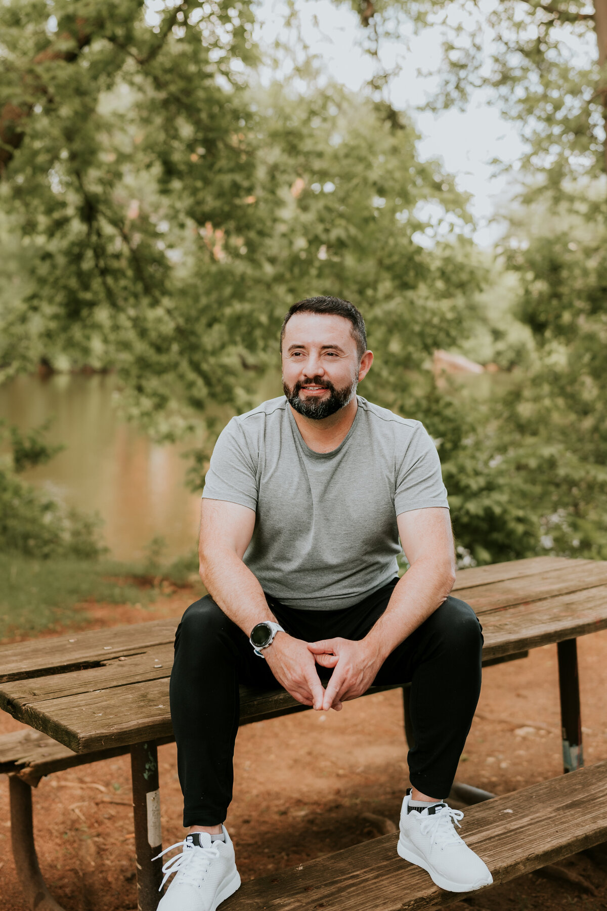 Relaxed dating profile photo of a man sitting casually on a bench in a Minneapolis park, perfect for showing an approachable vibe on dating apps.