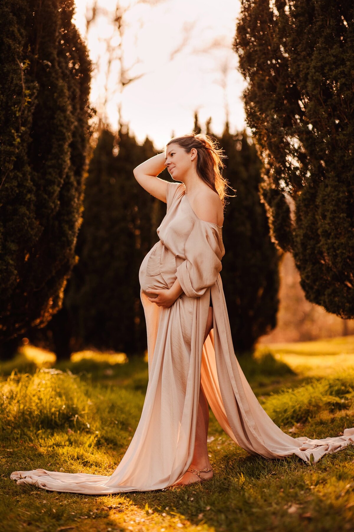 femme enceinte dans un parc se tenant le ventre avec une longue robe bohème