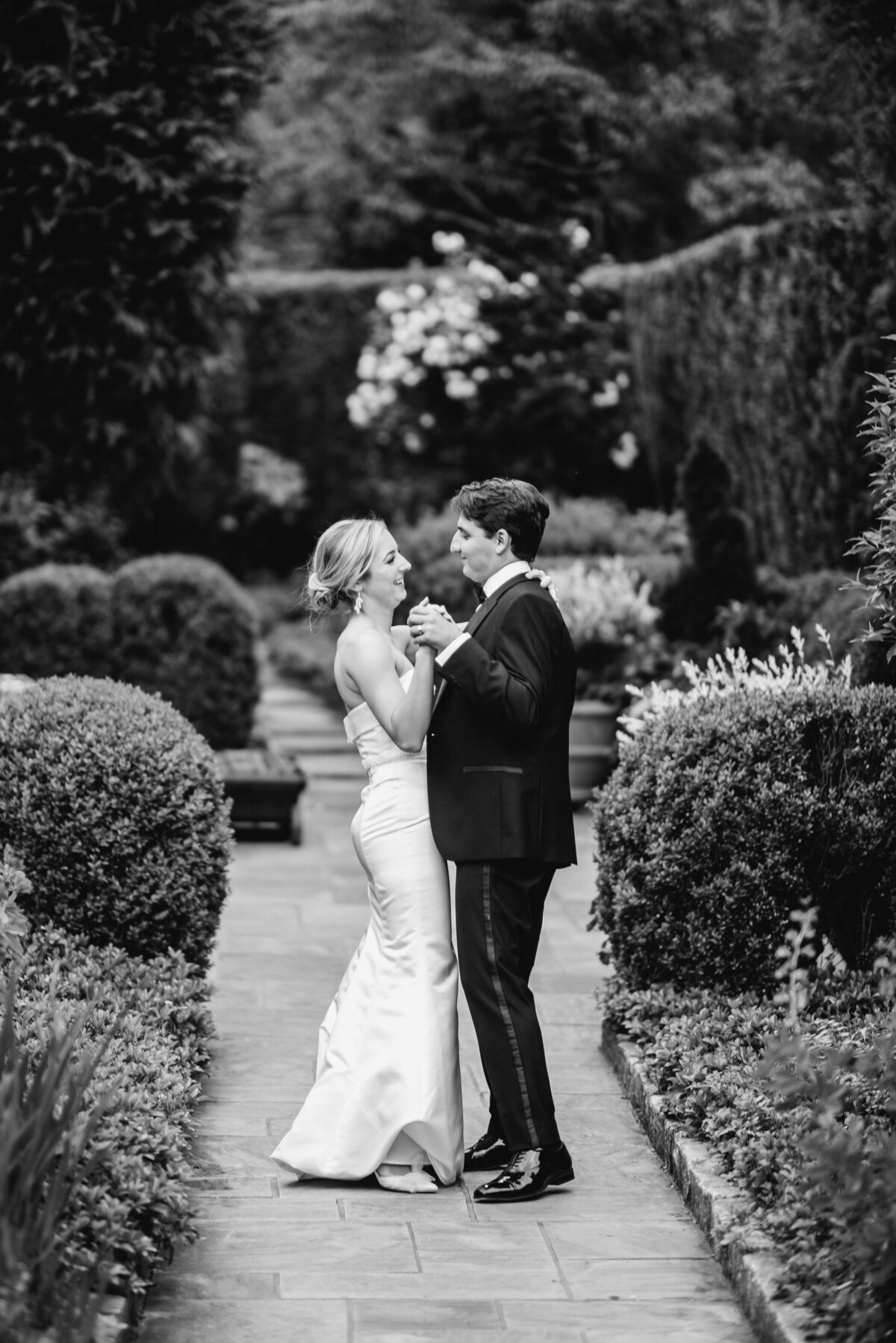 Black and White photo of bride and groom dancing together on a garden path at Old Edwards Inn in Highlands, NC.