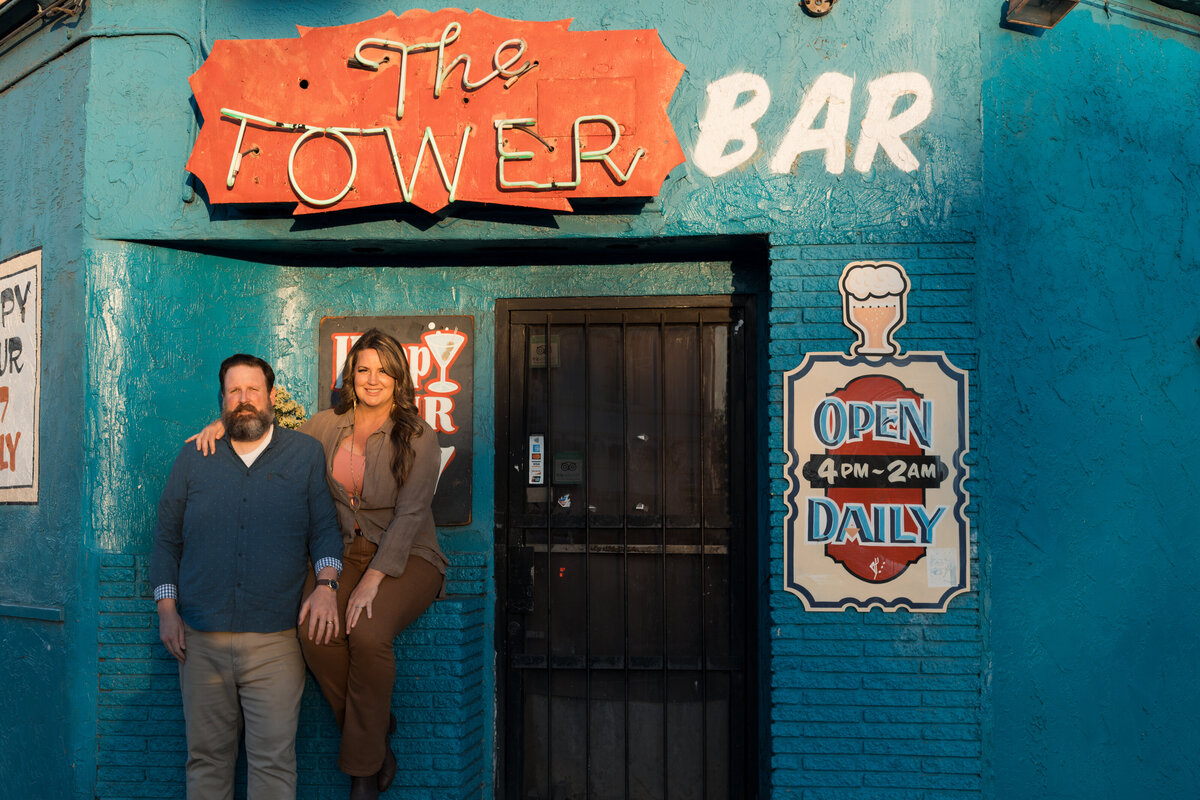 Beth and Mike Royal posed in front of a bright blue wall of the Tower Bar in San Diego