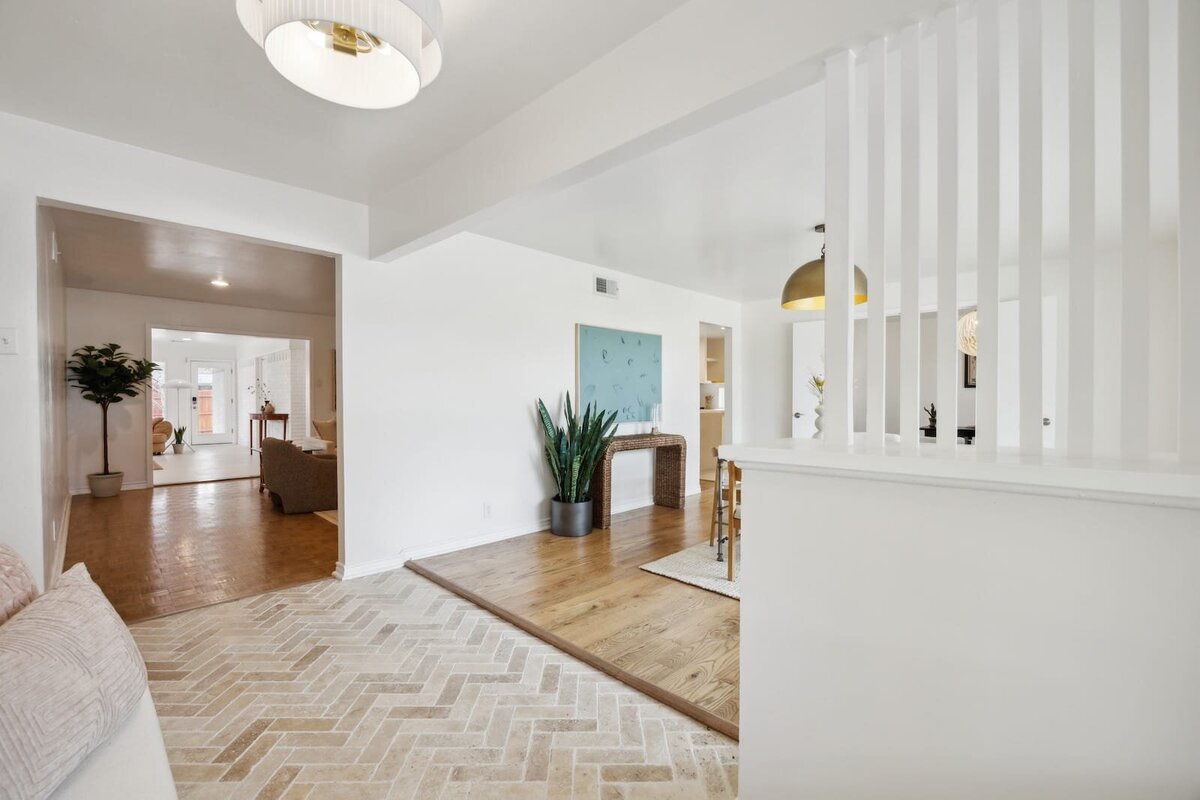 Front entryway of 3120 Chapel Downs Dr in Dallas TX showcasing herringbone brick tile, mid-century architectural divider, open-concept layout with natural light and hardwood floors – listed by Haven Realty Group.