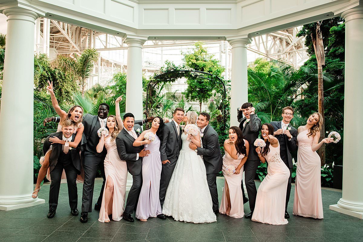 Bridesmaids and groomsmen celebrating with newlywed couple in Gaylord Opryland arbor