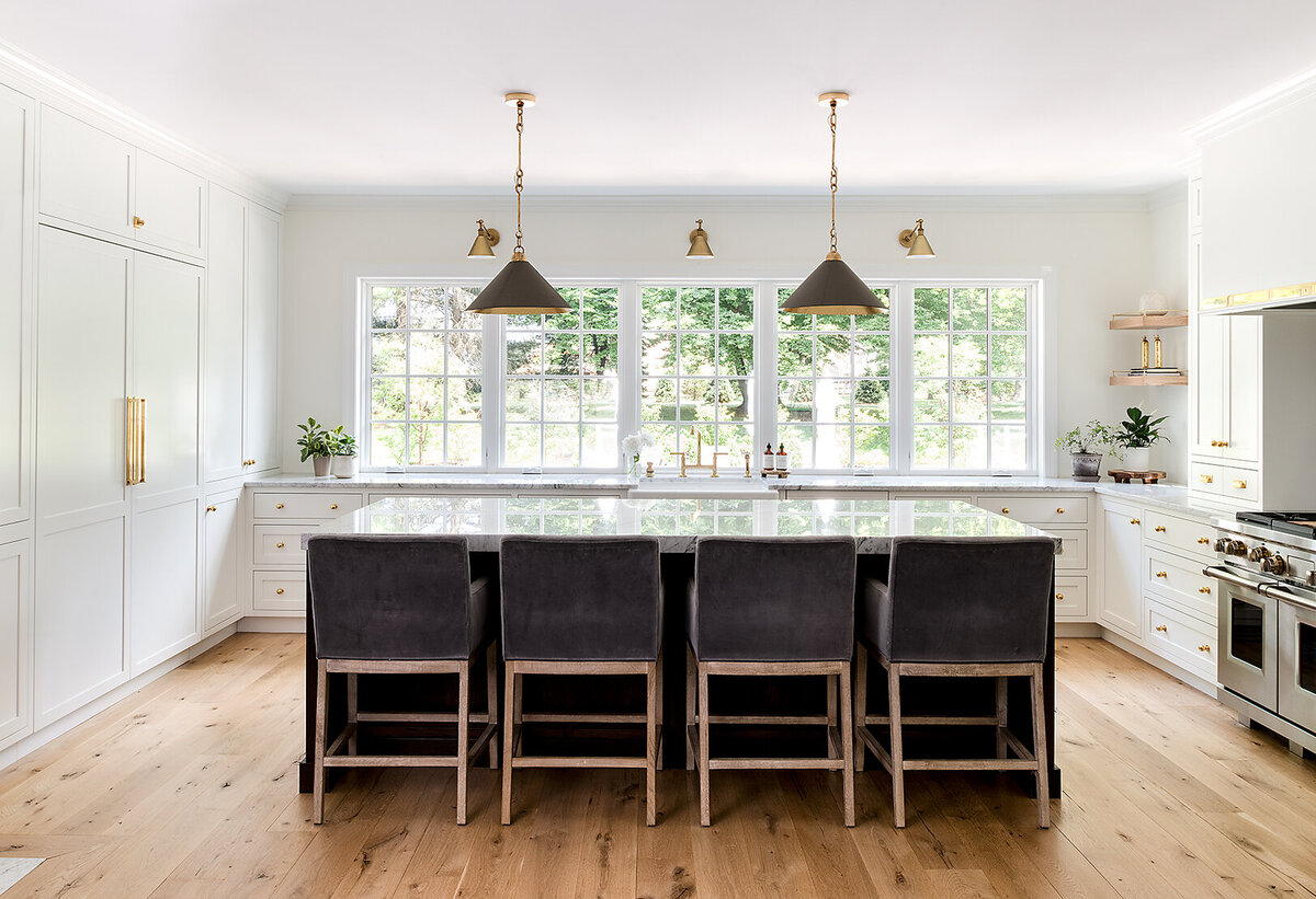 bright white kitchen with windows and large island top in the middle