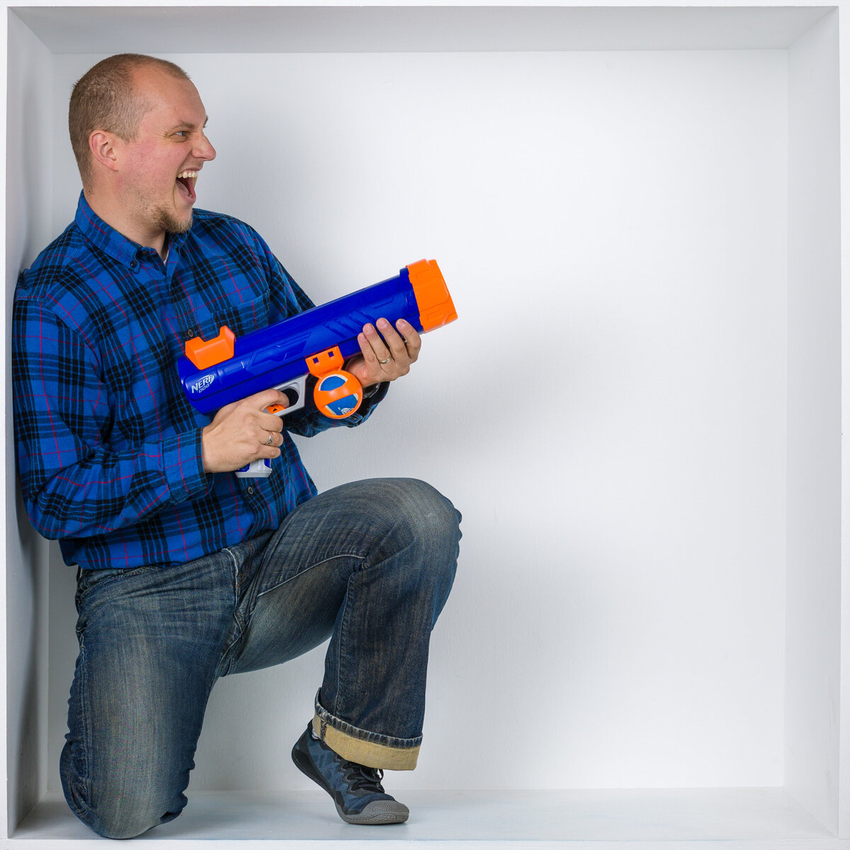 Headshot and branding photographer Travis from Fox & Brazen with a Nerf gun in  a white box