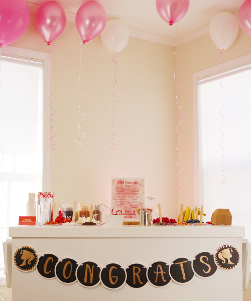 White snack cart with pink balloon party setup