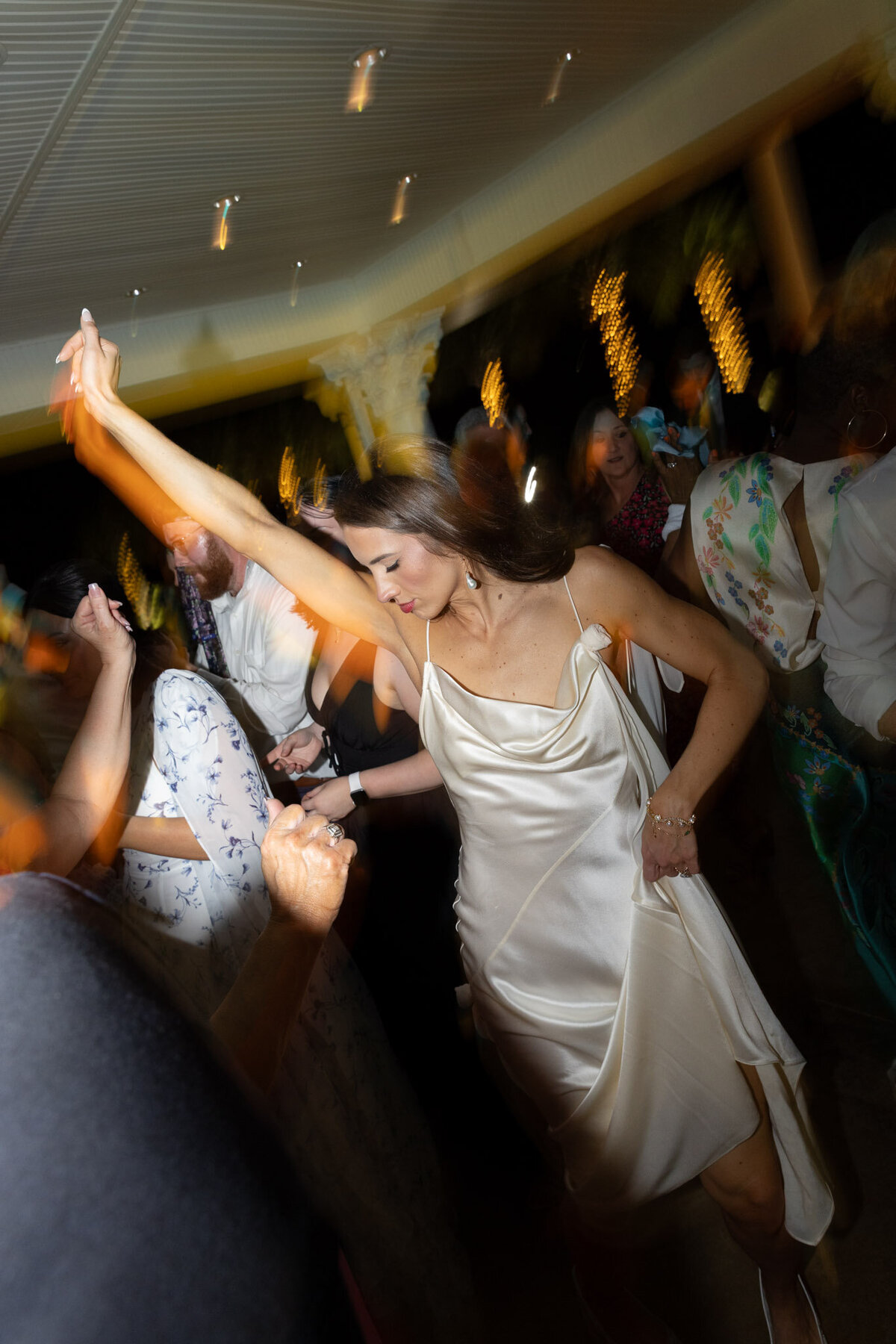 A slightly blurry photo taken with flash during a wedding reception of the bride dancing.