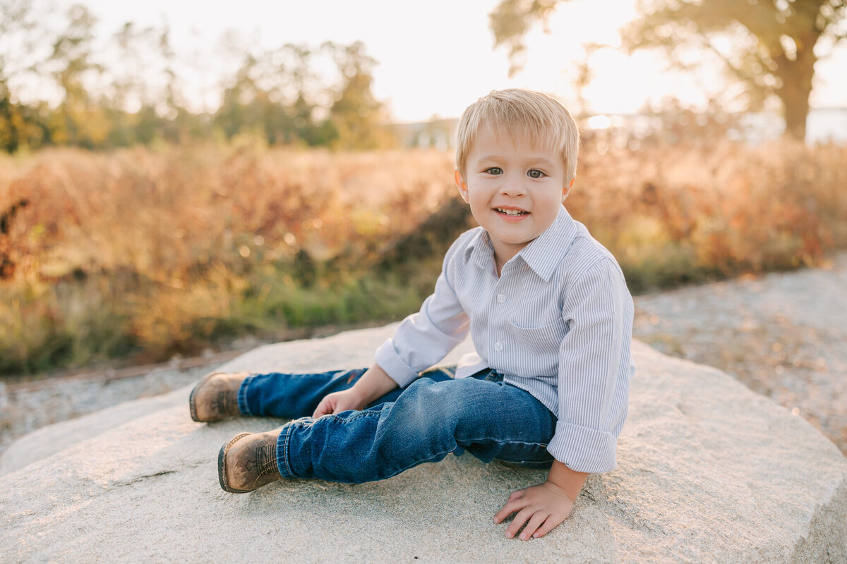 three year old sitting on a rock during his family session