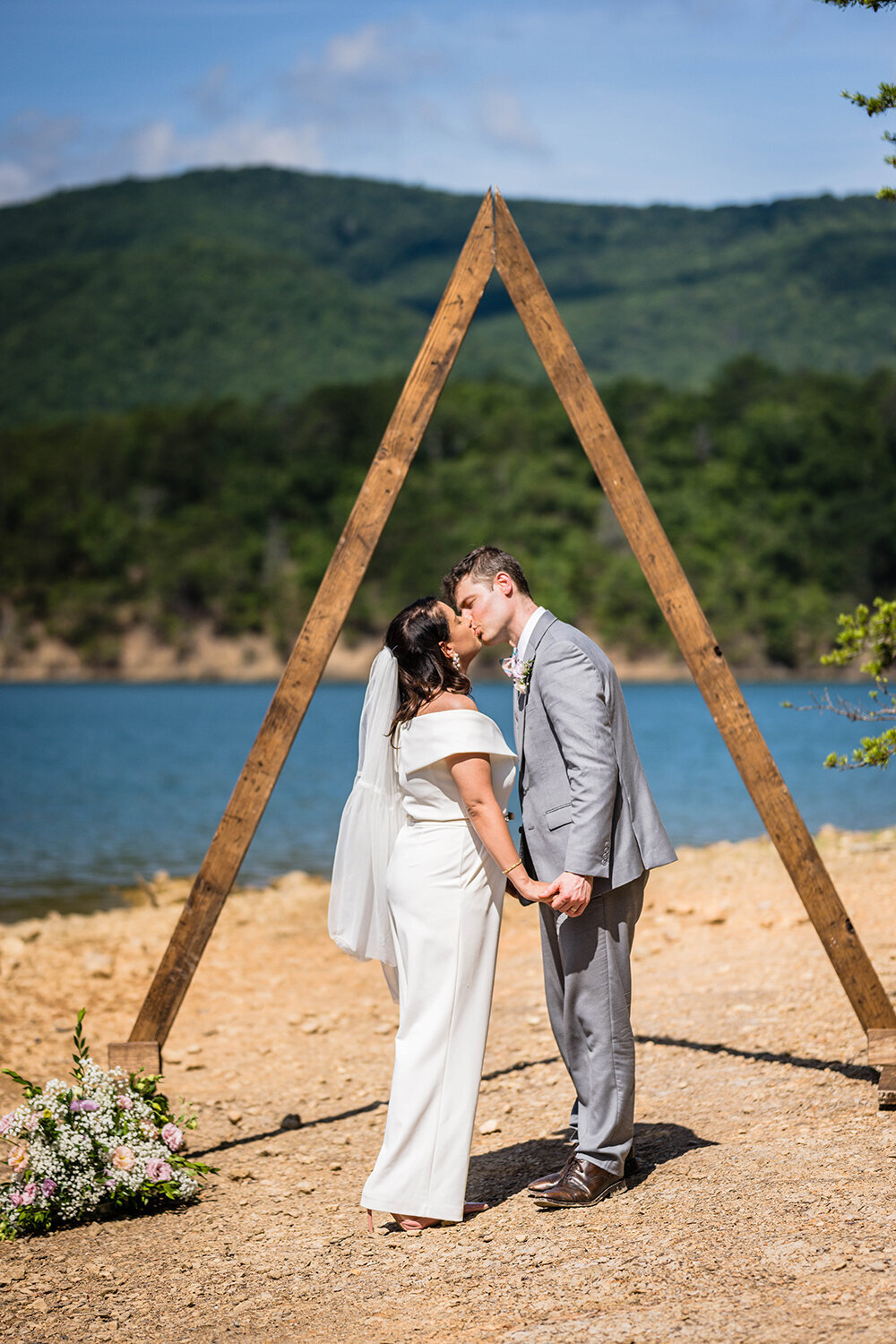 Two marriers go in for a first kiss under a triangle arch on Carvin’s Cove in Roanoke, Virginia.