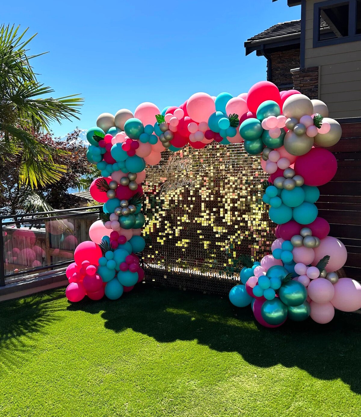 gold shimmer wall with pink and teal balloons