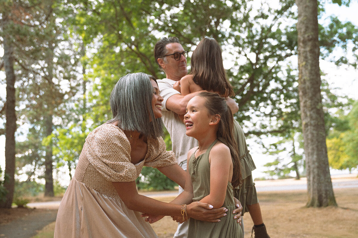 Parents playing and laughing with their daughters outdoors during a relaxed Irvine family session.